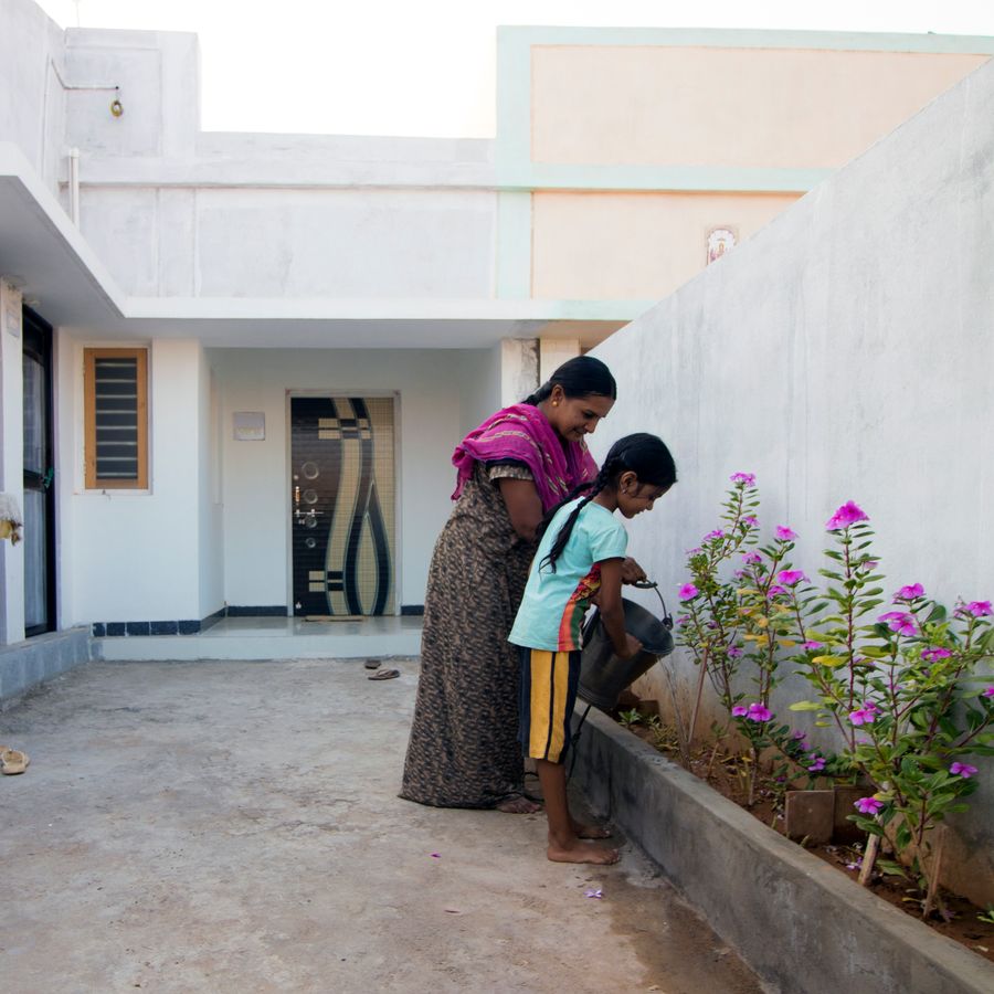 A woman and a young girl are in the courtyard of a house.