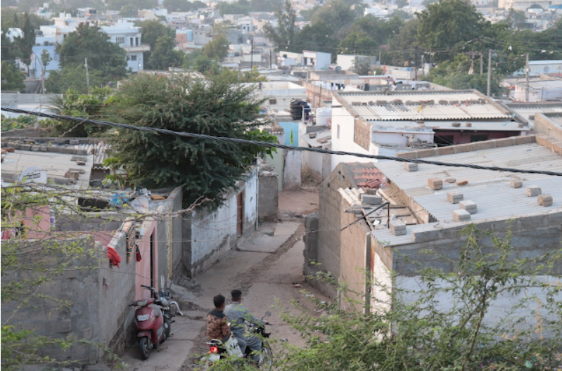 2 men going on a bike, through a congested housing settlement