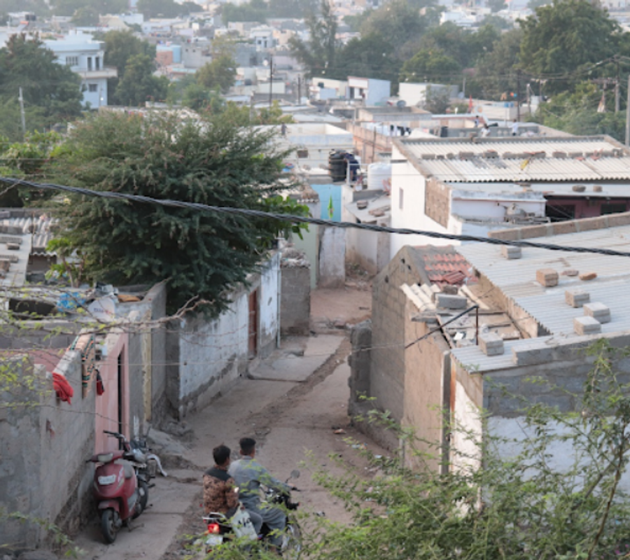 2 men going on a bike, through a congested housing settlement