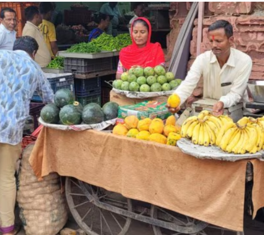 A street vendor with fruits to sell. A women standing near to him.
