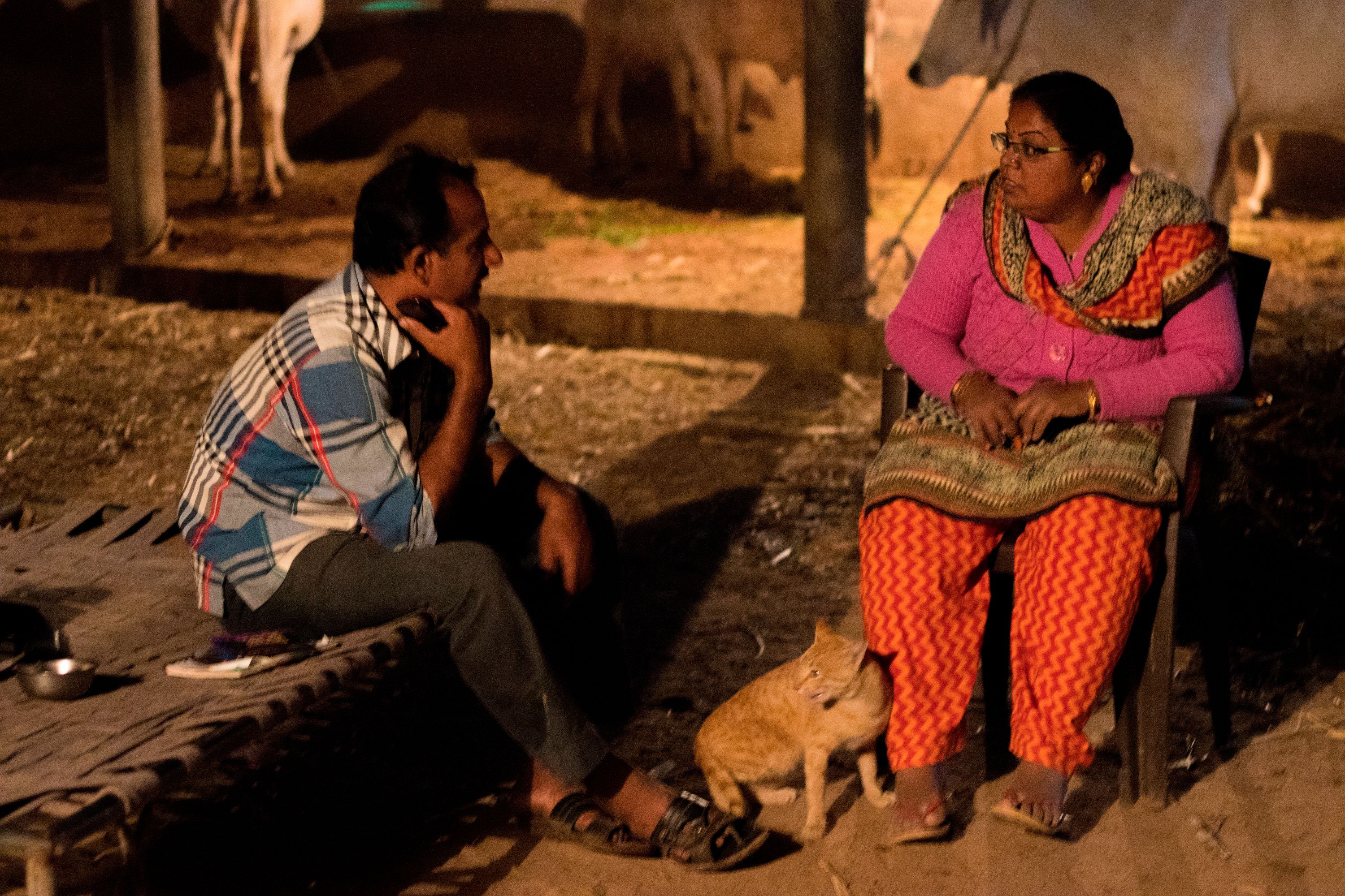 a man sitting on a cot on the left and a woman on a chair on the right side have a conversation