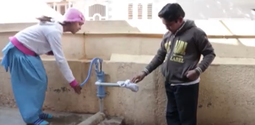 One girl and boy collecting water from a borewell.