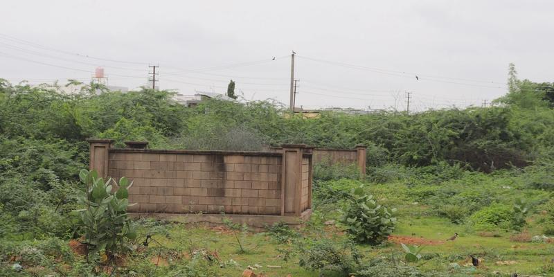 An old well like structure amidst green shrubs and bushes growing around it and the sky above.