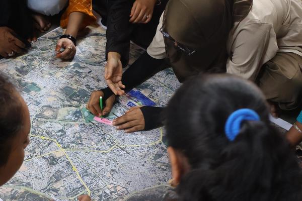 7 to 9 youth sitting on floor. They are marking the places on the map placed at centre of them.
