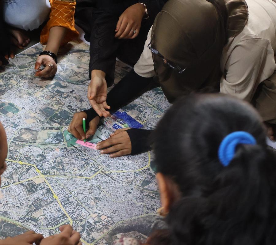 7 to 9 youth sitting on floor. They are marking the places on the map placed at centre of them.