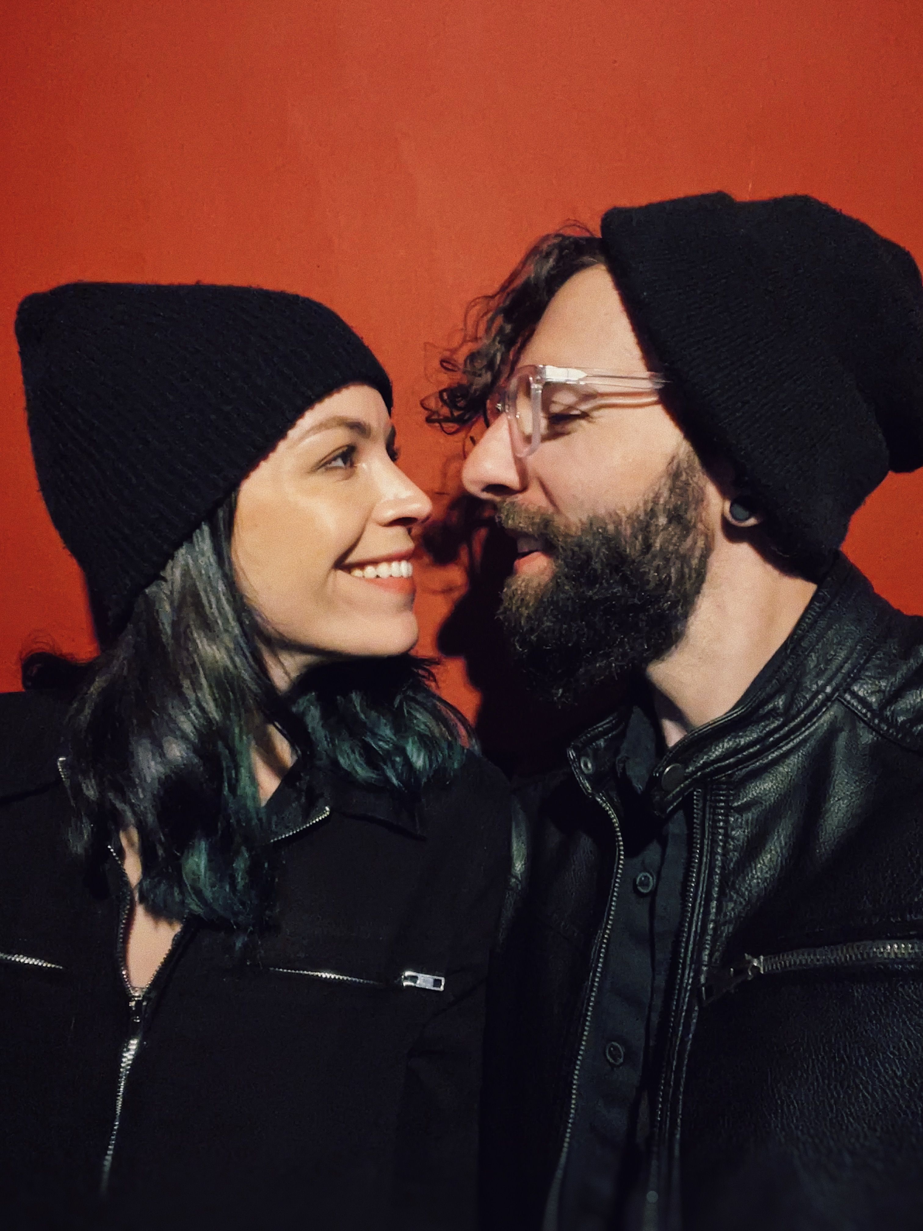 Nick and Kristin looking at eachother against a red background