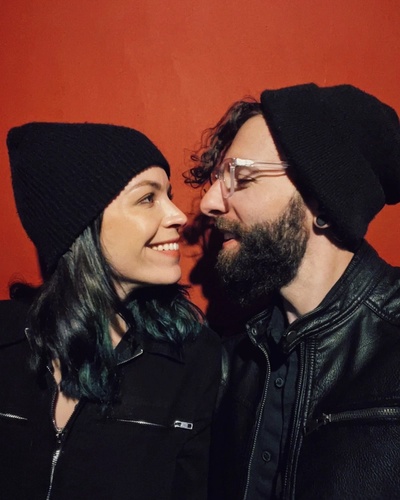 Nick and Kristin looking at eachother against a red background