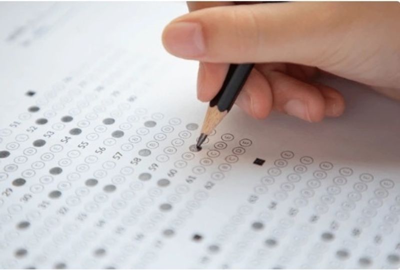Student filling in an exam multiple-choice answer sheet, practising effective study and exam techniques