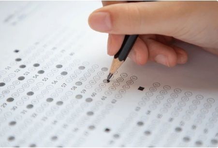 Student filling in an exam multiple-choice answer sheet, practising effective study and exam techniques