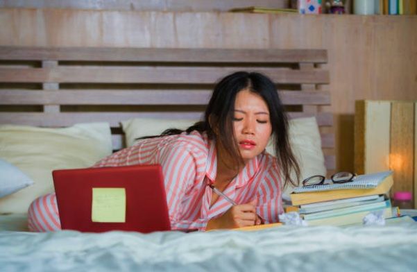 Secondary school student studying in bed and struggling to concentrate, illustrating poor study habits
