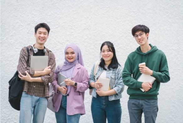 Group of Singapore university students and tutors standing together with books and notebooks.