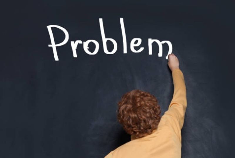 Student writing the word ‘problem’ on a board, symbolising tackling the hardest subject first in their study routine