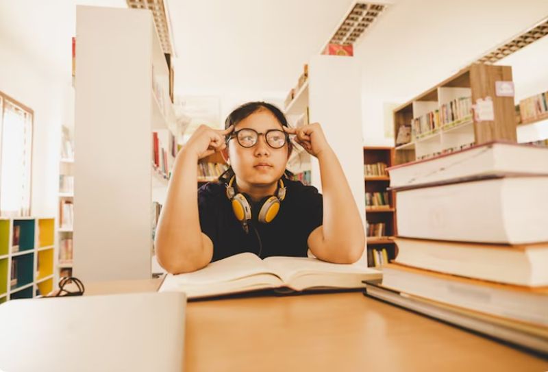 Secondary school student feeling stressed while studying in the library, highlighting the challenges of the Sec 3 to Sec 4 transition