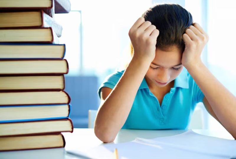 Student overwhelmed by heavy study materials, illustrating the academic pressure of moving from Sec 3 to Sec 4.