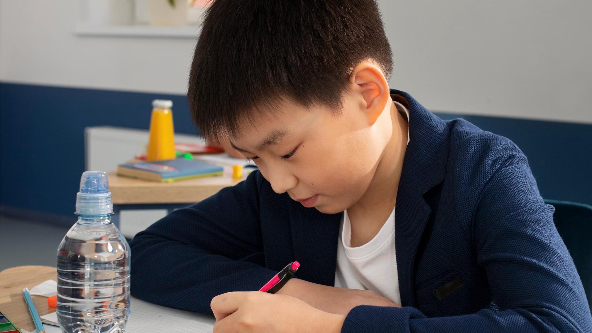 Primary school student solving a PSLE Math model drawing problem at a desk