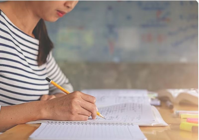 Student summarising study notes in a notebook as part of an effective study technique instead of highlighting