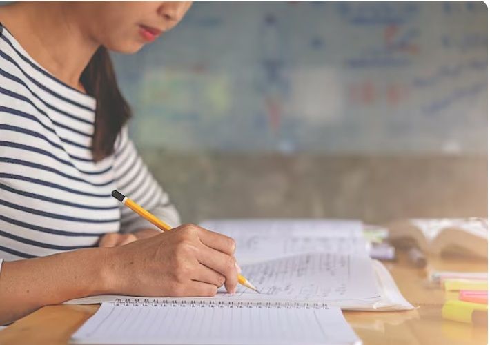 Student summarising study notes in a notebook as part of an effective study technique instead of highlighting
