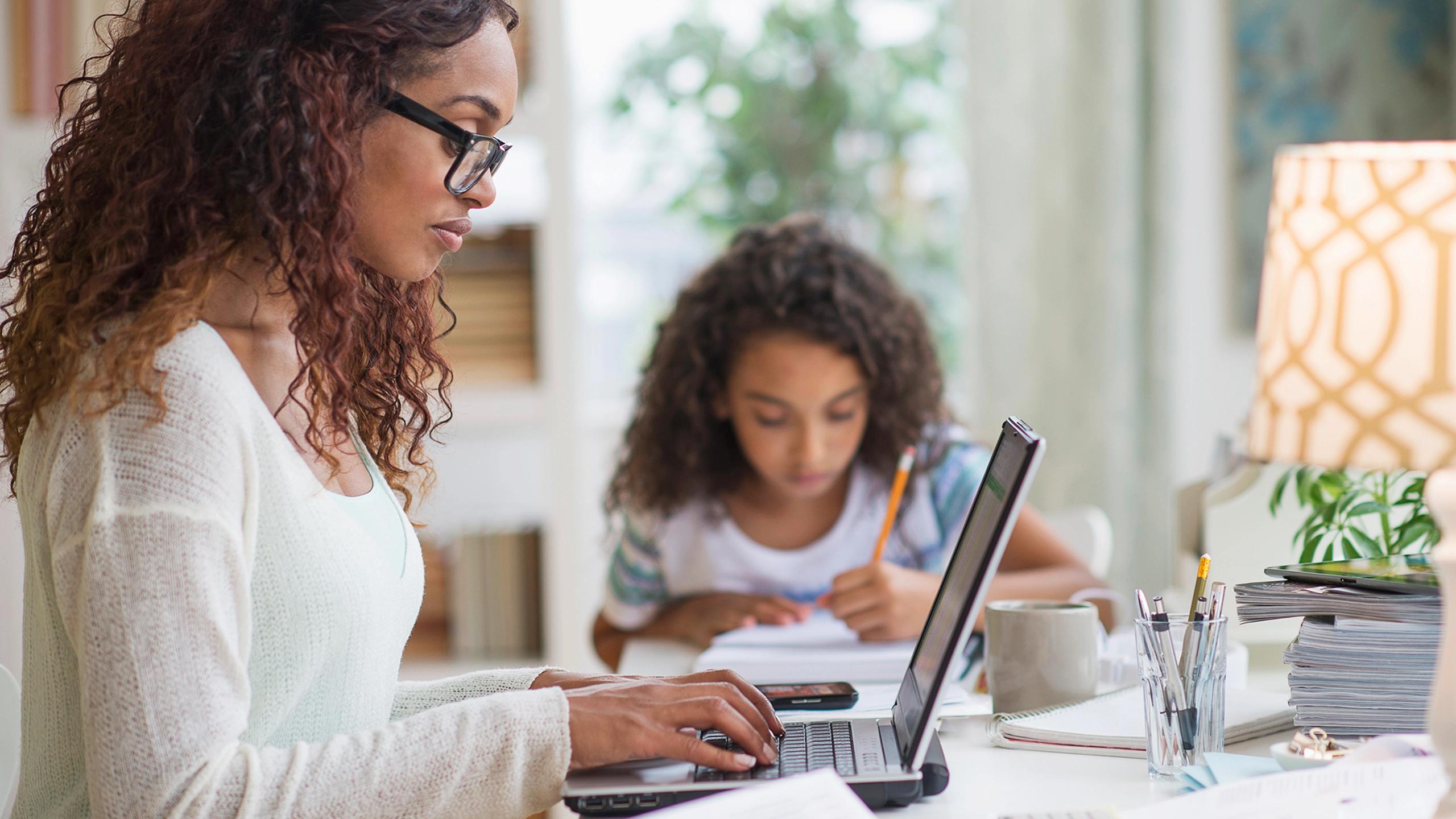 Woman on computer with child nearby.