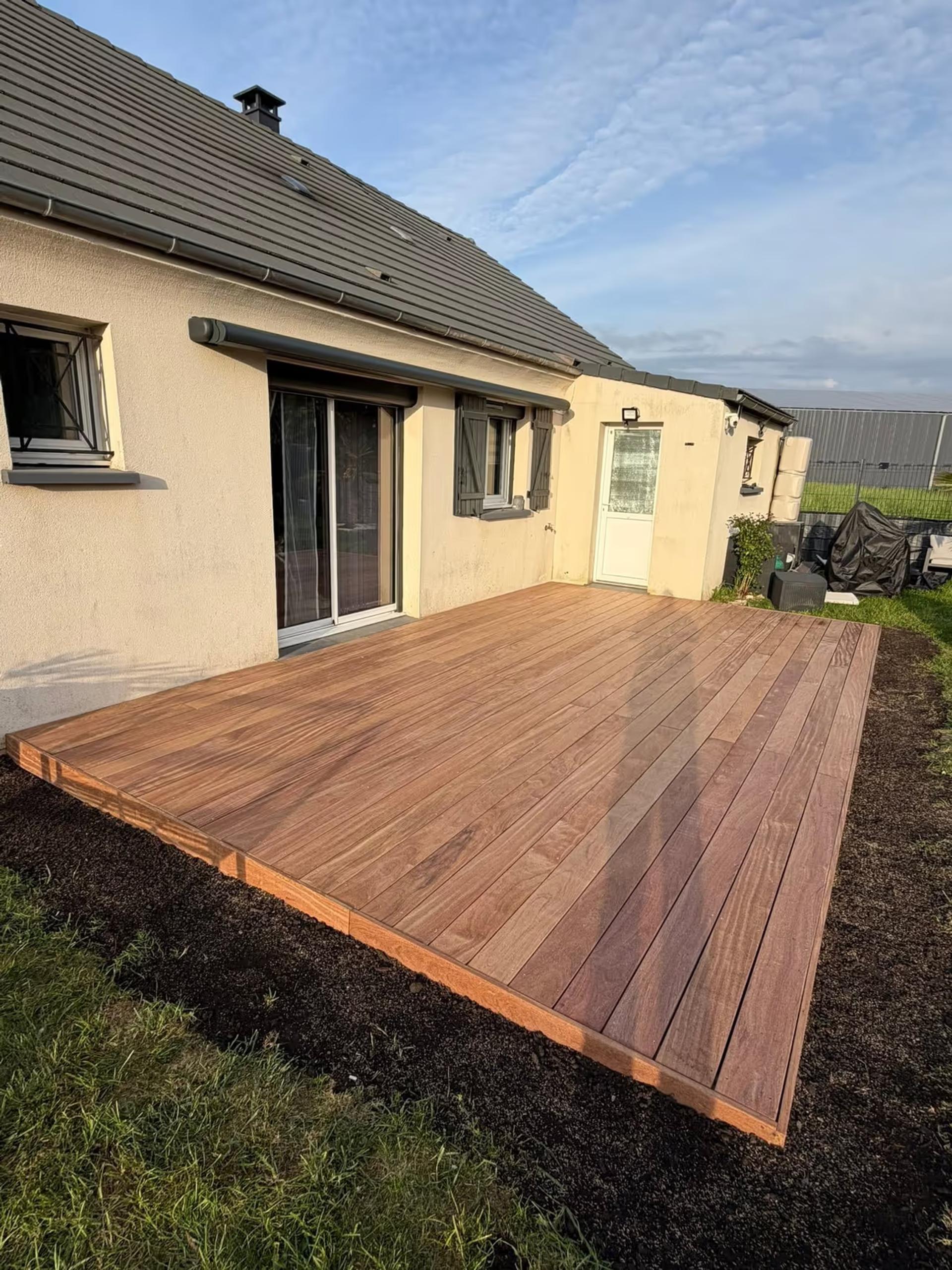 Terrasse en lames de bois exotique posée le long d’une maison