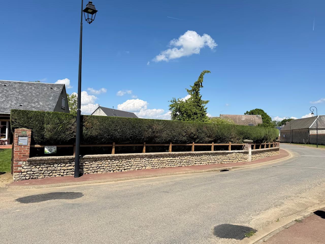 Haie taillée au carré le long d’une rue de village
