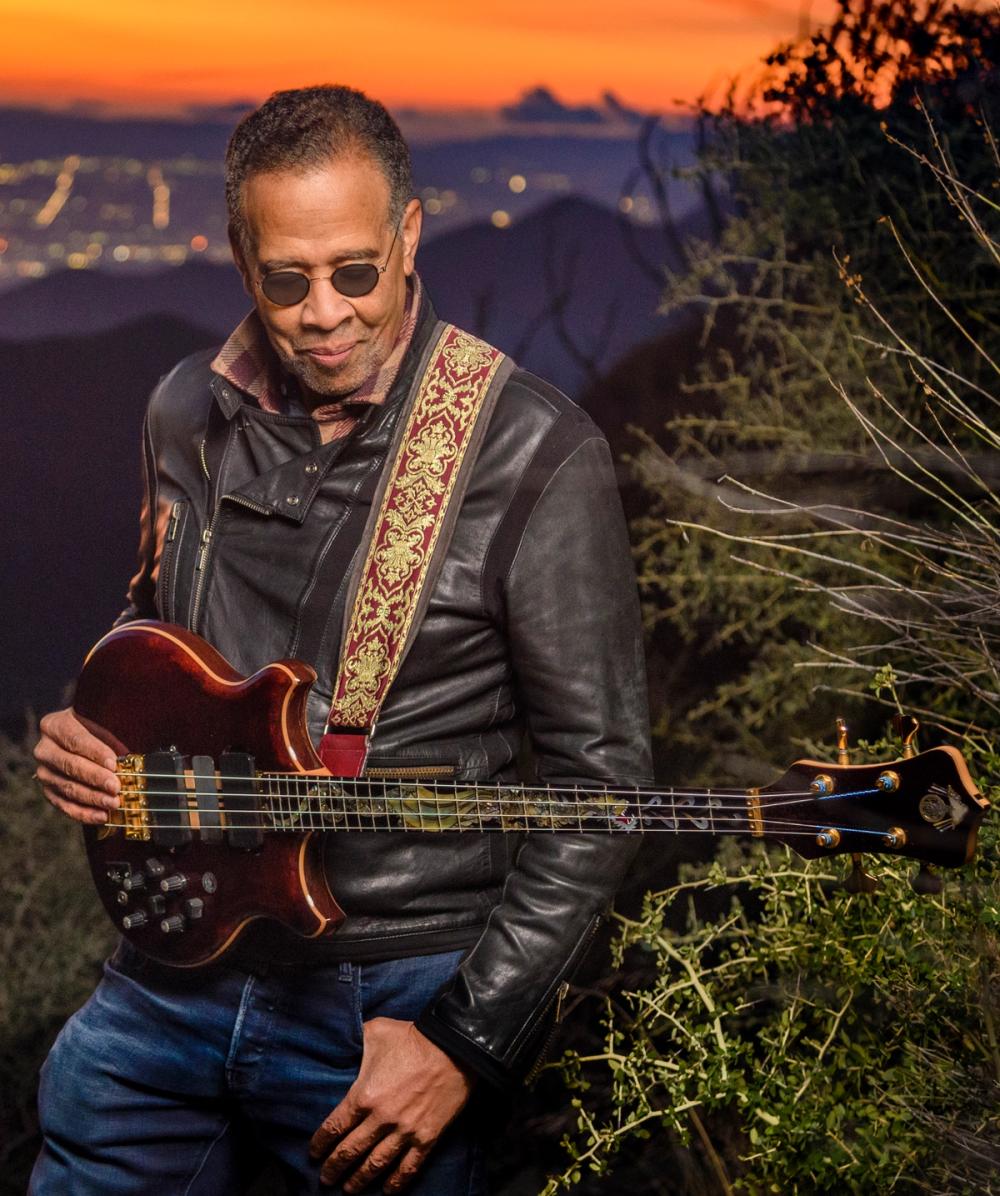 Stanley Clarke and his electric bass on a hillside at sunset with Los Angeles in the background