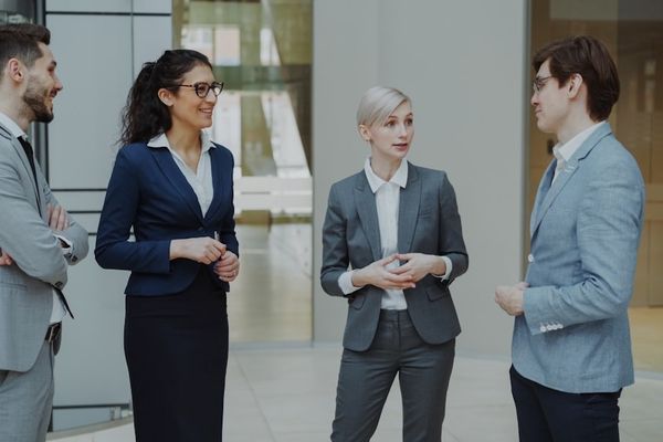 Four business professionals conversing in a modern office lobby.