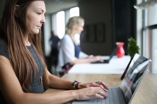 woman in white tank top using laptop computer