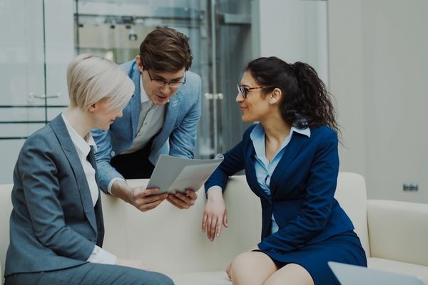 Three business people in suits discussing documents.