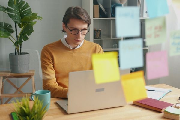 Man working on a laptop with sticky notes