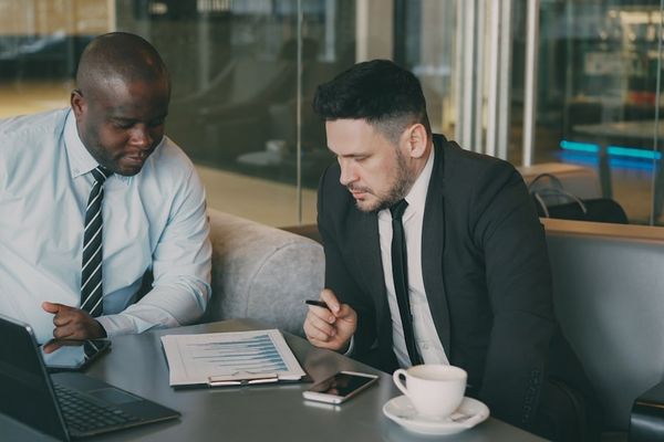 Two businessmen reviewing documents at a table.
