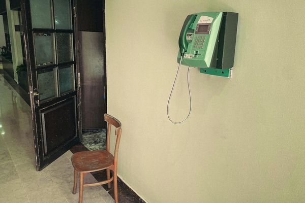 a chair next to a phone on a wall