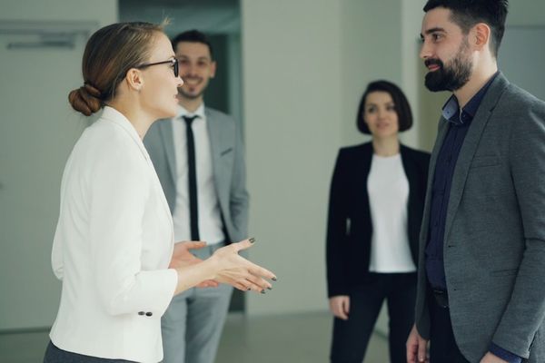 Two business people conversing, others observing.