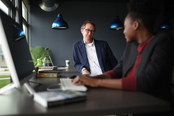 a man and a woman sitting at a desk in front of a computer