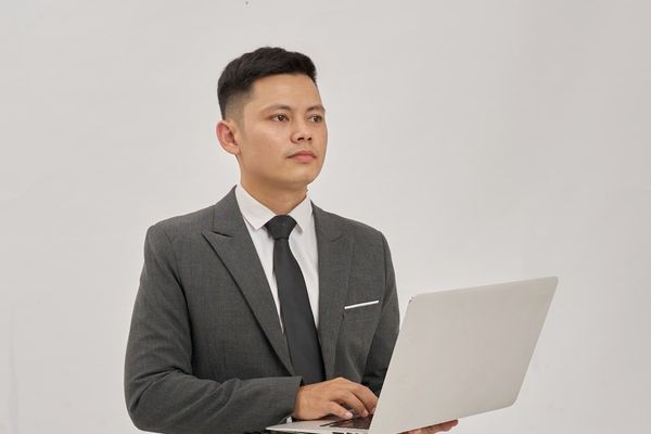 A businessman is holding a laptop and looking up.
