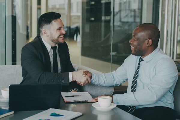 Two businessmen shaking hands across a table.