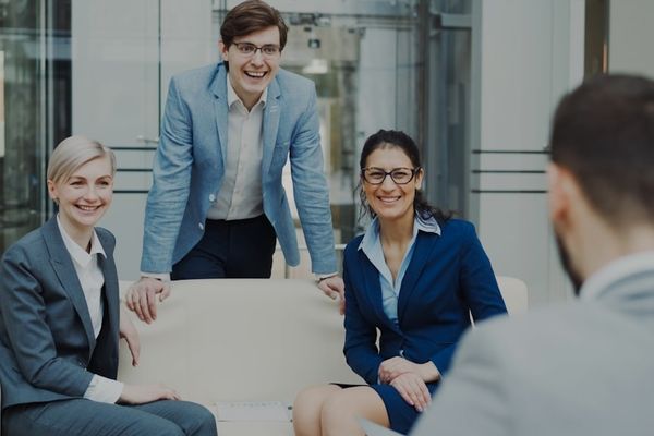 Four smiling business people in a modern office.