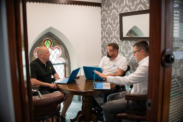 Three men in a meeting with laptops.