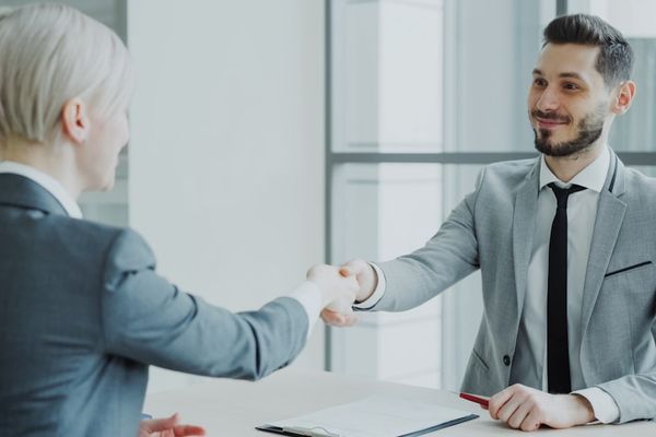 Two professionals shaking hands across a table.