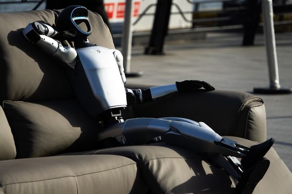 Robot relaxes comfortably on a couch.