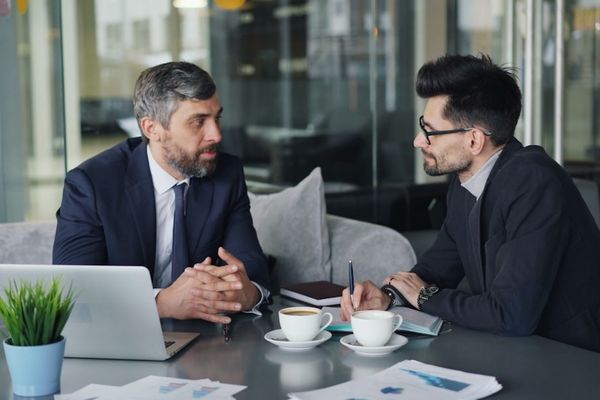 two men sitting at a table having a conversation