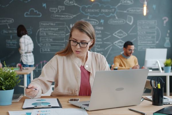 Woman working at desk with laptop and charts.