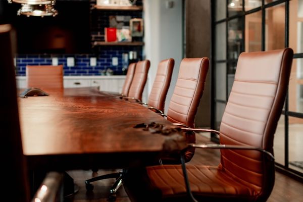 A conference room with a large wooden table and leather chairs
