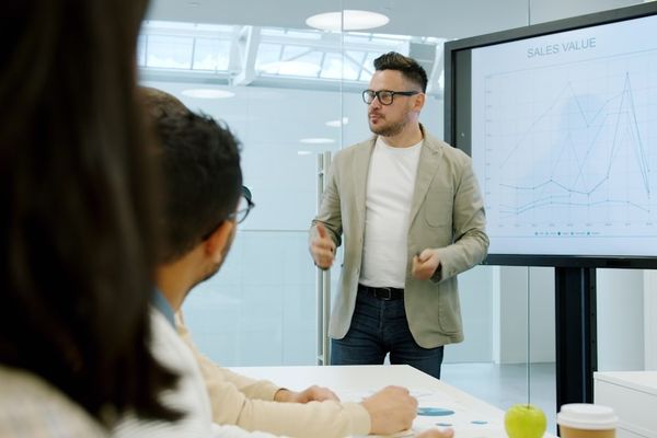 Man presenting data on a large screen to colleagues.