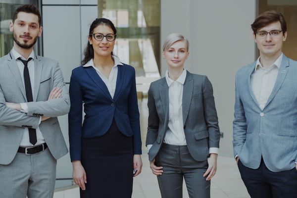 Four business professionals standing together indoors.