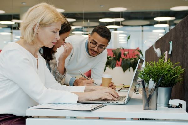Three people working together on a laptop.