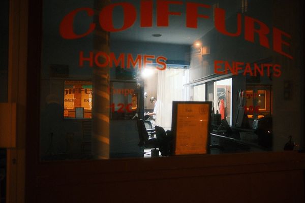 Hairstylist salon at night with "coiffure" sign