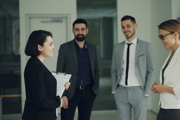 Four professionals in suits discussing in an office.