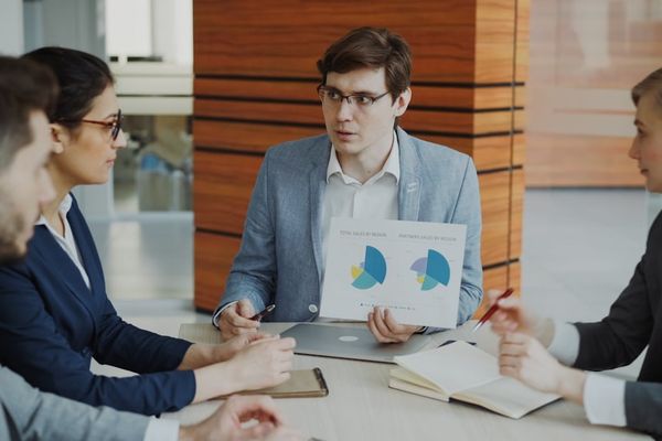 Man presenting charts to colleagues in a meeting.