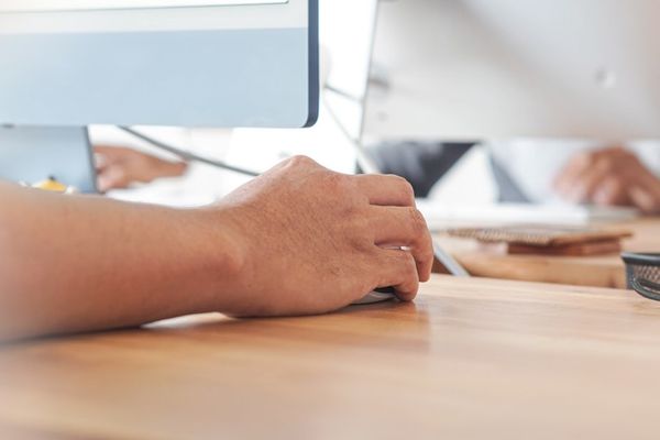 a person using a computer on a wooden desk