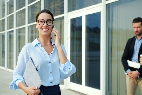 Woman in glasses talking on phone outside office building